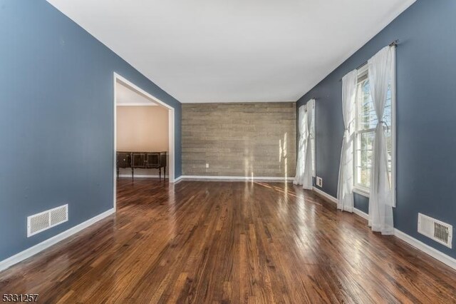 unfurnished room featuring dark wood-type flooring and a wealth of natural light