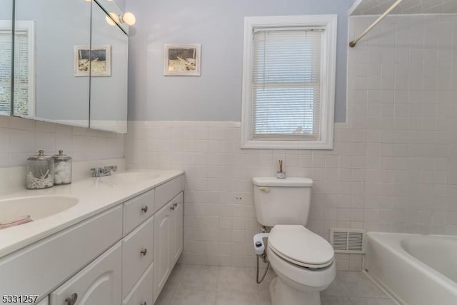 full bathroom featuring tiled shower / bath combo, tile patterned flooring, toilet, vanity, and tile walls