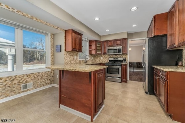 kitchen with a kitchen bar, appliances with stainless steel finishes, backsplash, kitchen peninsula, and sink