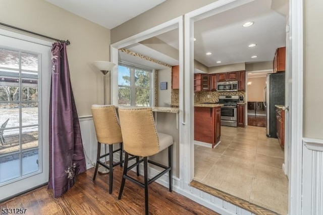 kitchen with a kitchen bar, kitchen peninsula, decorative backsplash, and appliances with stainless steel finishes