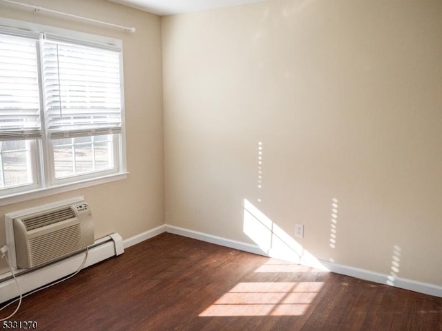 unfurnished room featuring dark hardwood / wood-style flooring, an AC wall unit, a wealth of natural light, and a baseboard heating unit