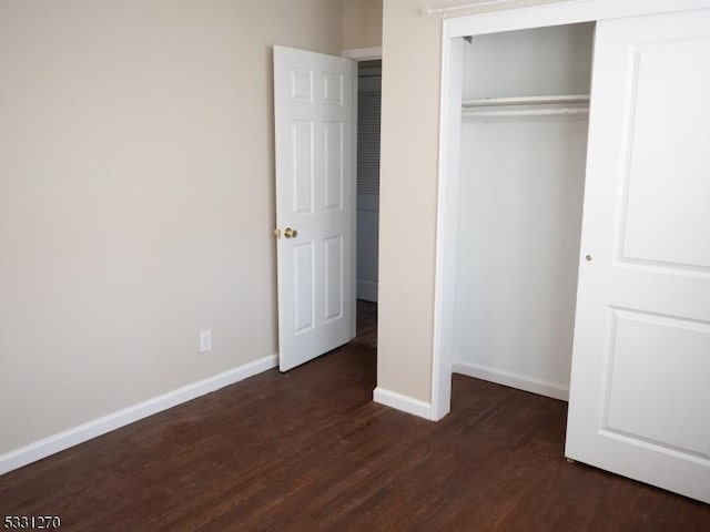 unfurnished bedroom featuring dark hardwood / wood-style flooring and a closet