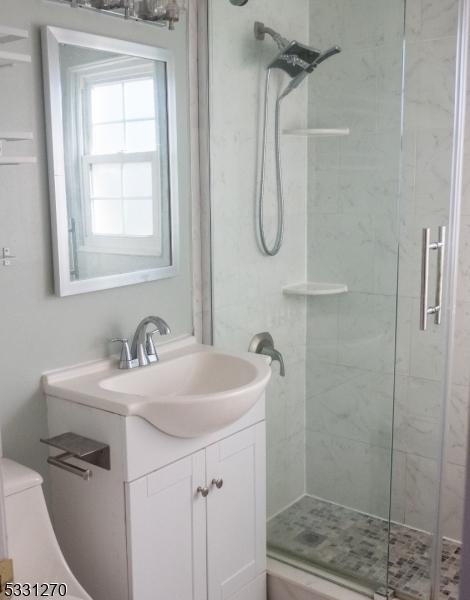 bathroom featuring a shower with door and vanity