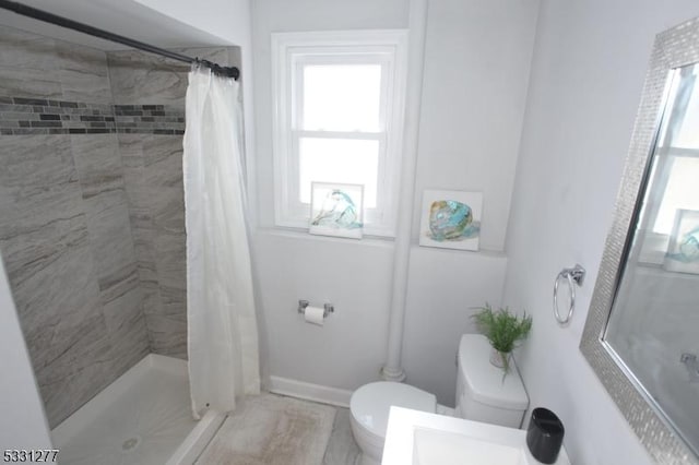 bathroom featuring a healthy amount of sunlight, a shower with shower curtain, and toilet