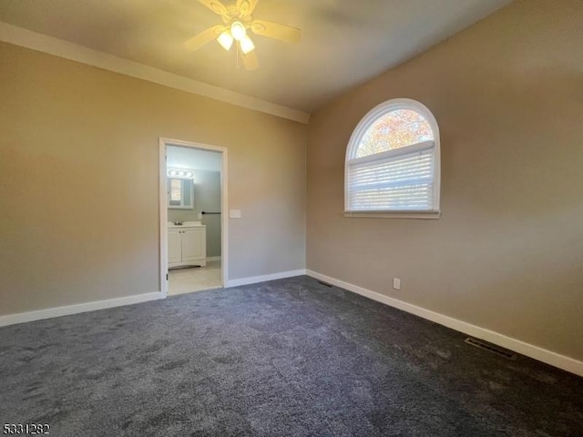 carpeted spare room featuring ceiling fan, ornamental molding, and vaulted ceiling