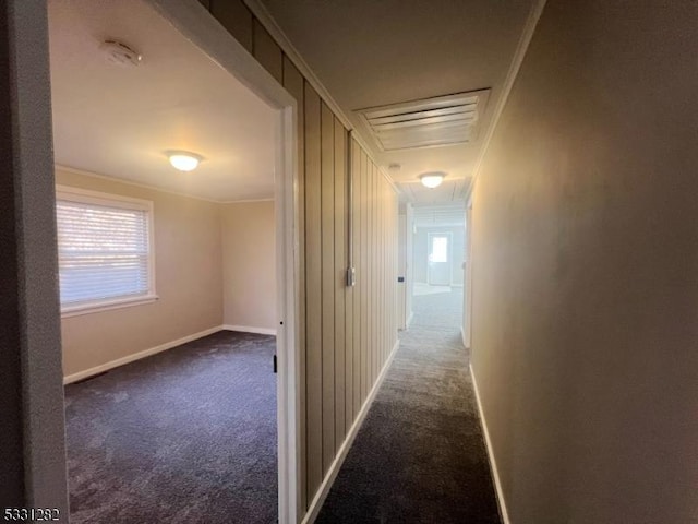 hallway with dark carpet, plenty of natural light, and ornamental molding