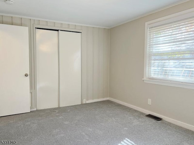 unfurnished bedroom featuring carpet flooring, ornamental molding, and a closet