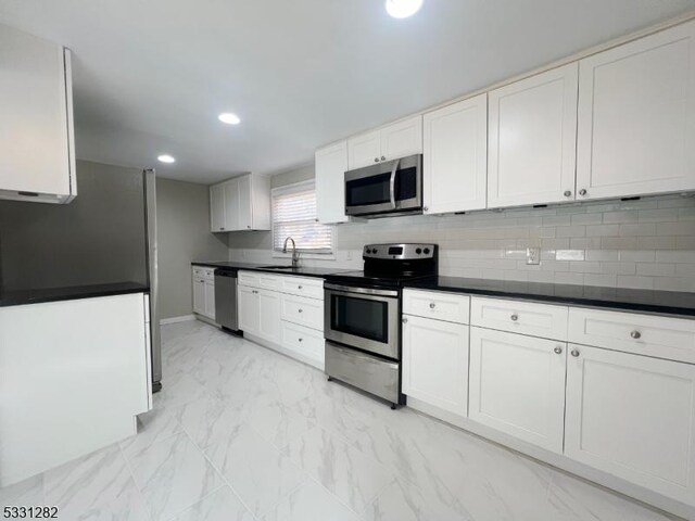 kitchen with tasteful backsplash, sink, white cabinets, and stainless steel appliances