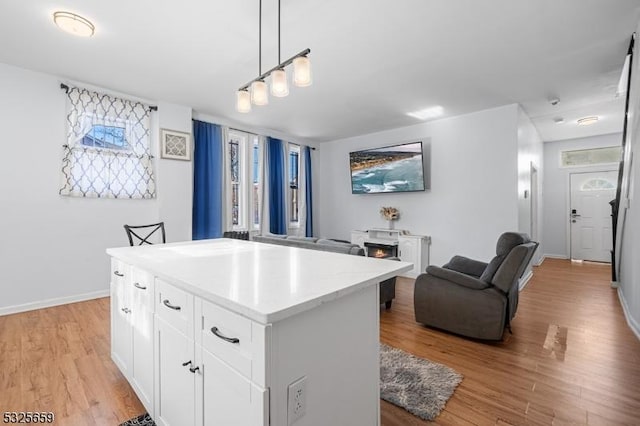 kitchen featuring white cabinets, light hardwood / wood-style floors, a kitchen island, and hanging light fixtures