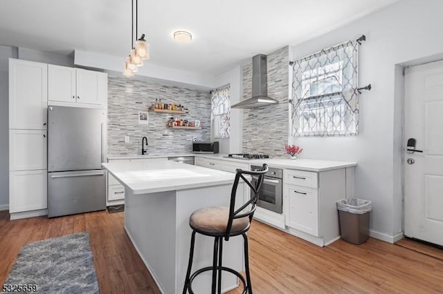 kitchen with wall chimney exhaust hood, white cabinetry, appliances with stainless steel finishes, and tasteful backsplash