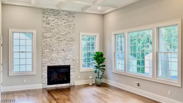 interior space featuring hardwood / wood-style flooring, beamed ceiling, coffered ceiling, and a fireplace