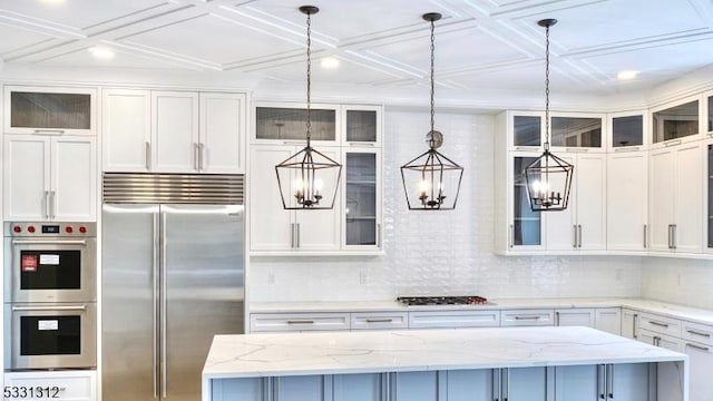 kitchen featuring hanging light fixtures, a center island, stainless steel appliances, and light stone countertops