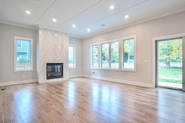 unfurnished living room featuring a fireplace, ornamental molding, and light hardwood / wood-style flooring