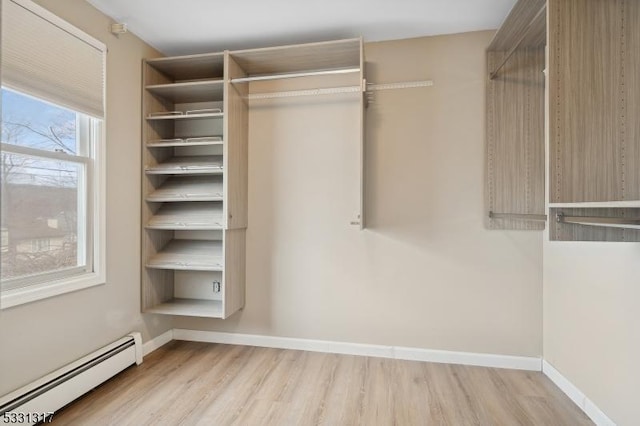 walk in closet featuring a baseboard heating unit and light hardwood / wood-style flooring