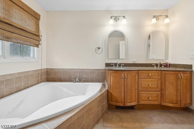 bathroom with a relaxing tiled tub, vanity, and tile patterned flooring