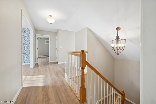 hall featuring a baseboard heating unit, light hardwood / wood-style flooring, and a notable chandelier