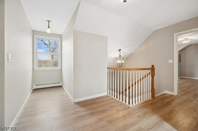 interior space featuring baseboard heating, vaulted ceiling, a notable chandelier, and light hardwood / wood-style floors