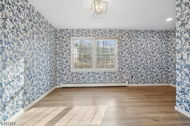 empty room with a baseboard radiator, wood-type flooring, and a notable chandelier