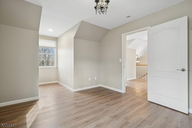 bonus room with vaulted ceiling, an inviting chandelier, and light hardwood / wood-style flooring