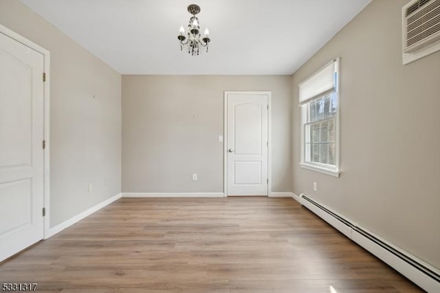 unfurnished room featuring a baseboard radiator, a wall mounted AC, a notable chandelier, and light wood-type flooring