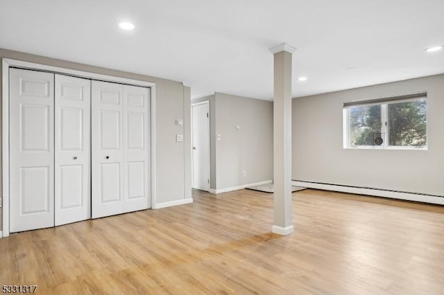 basement with a baseboard heating unit and light hardwood / wood-style flooring