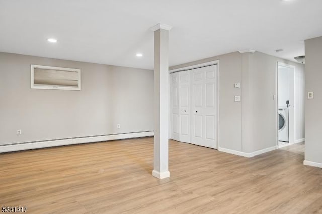 basement featuring washer / clothes dryer, baseboard heating, and light hardwood / wood-style floors