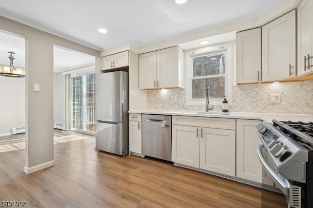 kitchen featuring sink, white cabinetry, light hardwood / wood-style flooring, appliances with stainless steel finishes, and a baseboard radiator