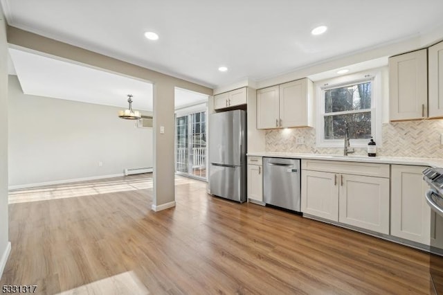 kitchen featuring appliances with stainless steel finishes, decorative backsplash, light hardwood / wood-style floors, and sink