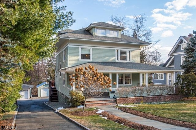 view of property with a porch, a garage, a front lawn, and an outdoor structure