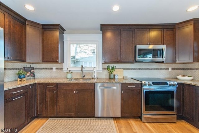 kitchen with tasteful backsplash, light stone counters, sink, and stainless steel appliances