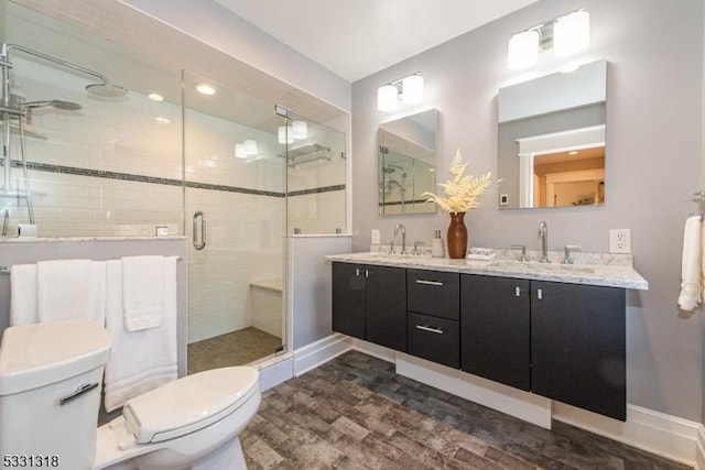 bathroom with hardwood / wood-style floors, vanity, a shower with door, and toilet