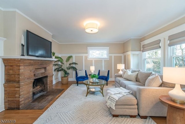 living room featuring hardwood / wood-style floors, ornamental molding, and a brick fireplace