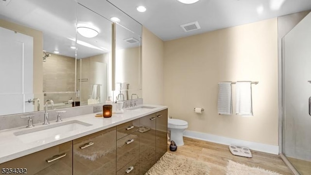 bathroom featuring hardwood / wood-style floors, vanity, toilet, and a shower with door