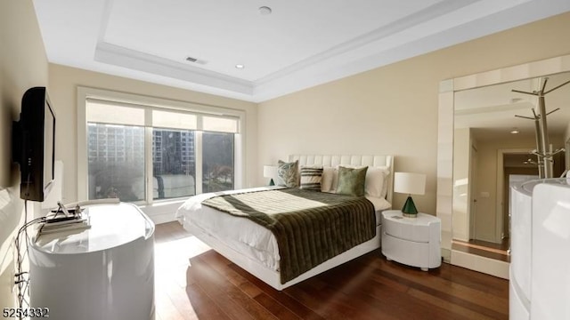 bedroom with dark wood-type flooring and a tray ceiling