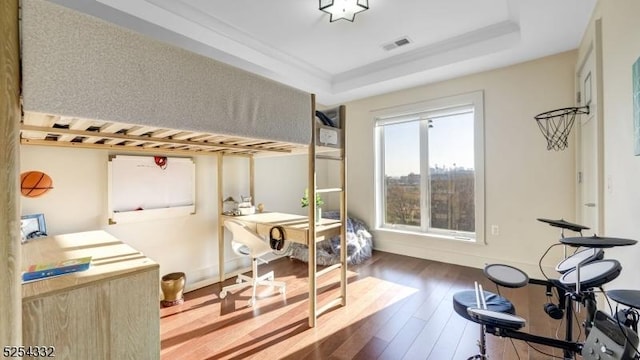 exercise room featuring a raised ceiling and dark hardwood / wood-style floors