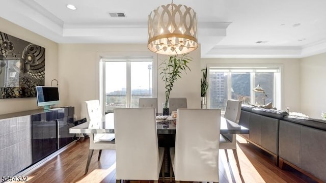 dining room featuring a raised ceiling, a notable chandelier, and hardwood / wood-style flooring