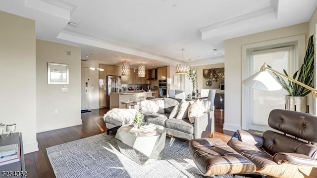 living room with dark hardwood / wood-style flooring and a tray ceiling