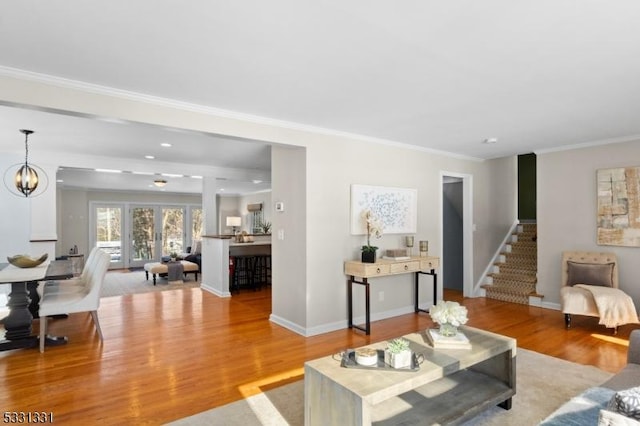 living room with crown molding, light hardwood / wood-style flooring, and a chandelier