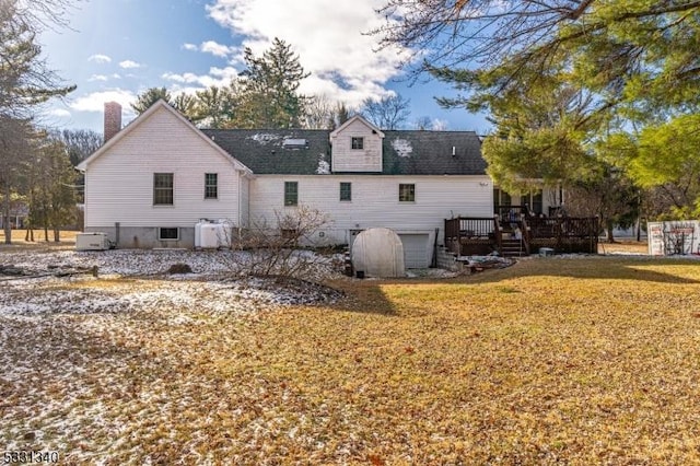 rear view of property featuring a lawn, a garage, and a wooden deck