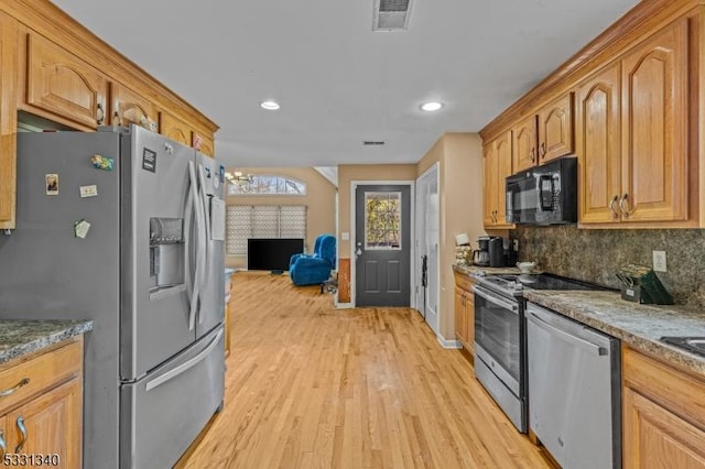 kitchen featuring backsplash, stone countertops, light hardwood / wood-style floors, and stainless steel appliances