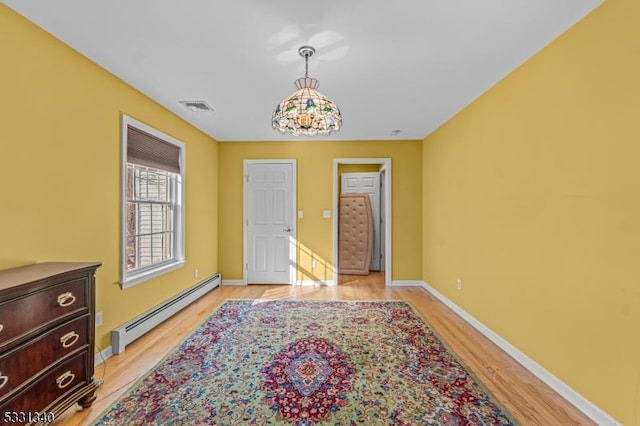 bedroom with light wood-type flooring and a baseboard heating unit