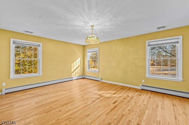 empty room with light hardwood / wood-style flooring, a healthy amount of sunlight, baseboard heating, and an inviting chandelier