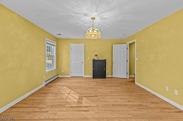 empty room featuring light hardwood / wood-style floors, an inviting chandelier, and baseboard heating