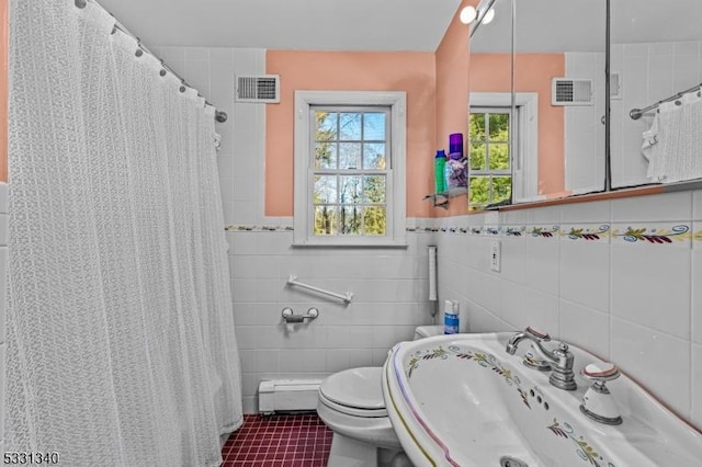 bathroom featuring sink, baseboard heating, tile patterned flooring, toilet, and tile walls