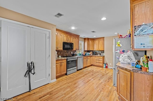 kitchen featuring decorative backsplash, light wood-type flooring, and appliances with stainless steel finishes