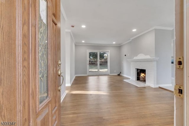 unfurnished living room with a brick fireplace, ornamental molding, and light wood-type flooring