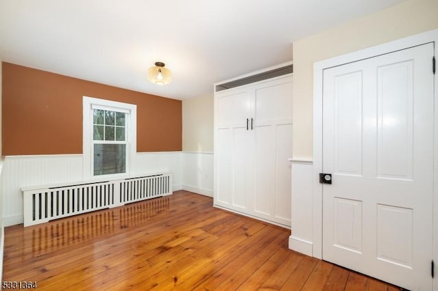 empty room featuring radiator heating unit and light hardwood / wood-style flooring