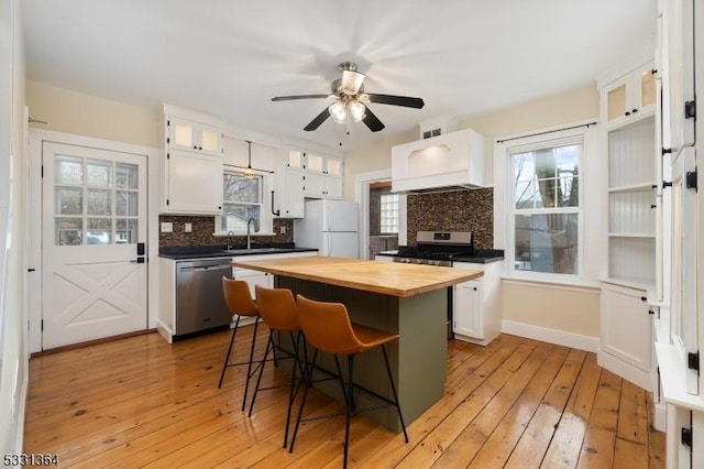 kitchen featuring white cabinets, a center island, stainless steel appliances, and wood counters