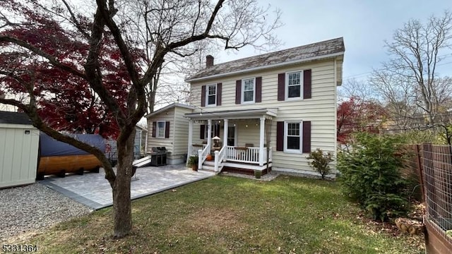 colonial inspired home with a patio area, covered porch, and a front lawn