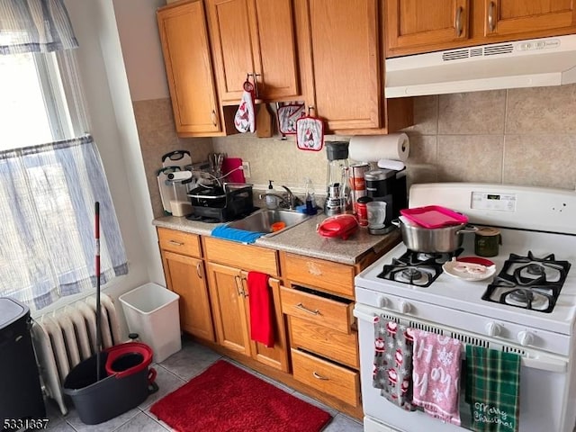 kitchen featuring backsplash, light tile patterned flooring, sink, and white gas range oven